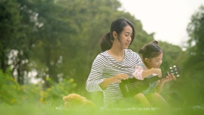 在公园野餐时，和她可爱的女儿玩夏威夷四弦琴