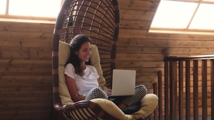 女人坐在带笔记本电脑的秋千吊床躺椅上