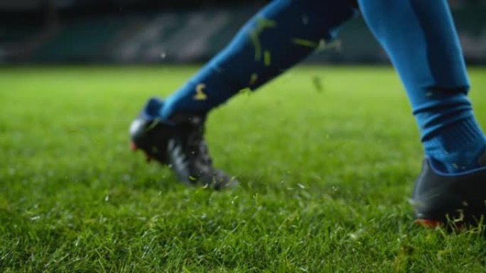 踢足球的靴子腿的特写镜头。职业足球运动员用凶猛的力量击球，进球，草地飞翔。超慢动作电影低角度地面艺术