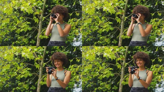 夏天在城市公园用单反相机在户外拍照的女人
