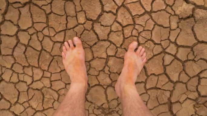 观点: 在破裂的沙漠地面上看到泥泞的赤脚