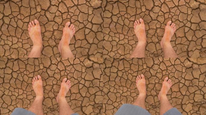 观点: 在破裂的沙漠地面上看到泥泞的赤脚