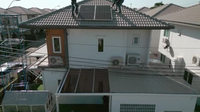 亚洲工人在房屋屋顶上安装光伏太阳能电池板。