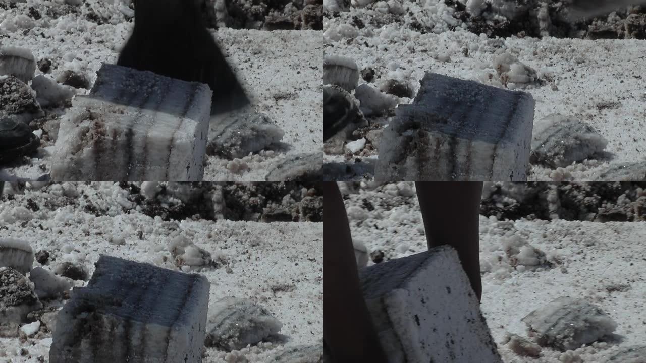 盐矿工人用斧头从阿根廷萨利纳斯·格兰德斯盐滩提取盐块。低角度视图。特写。