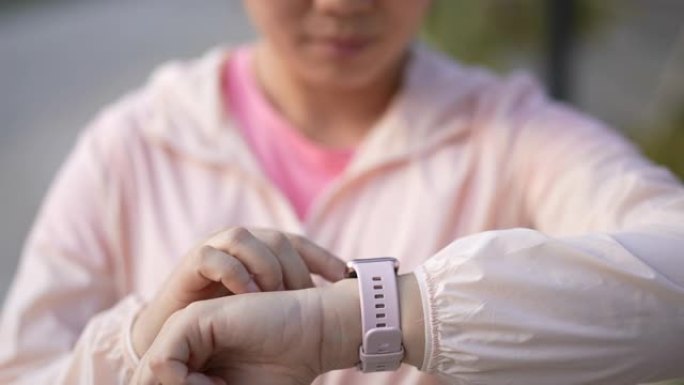 女人跑步和检查智能手表以监控她的跑步表现