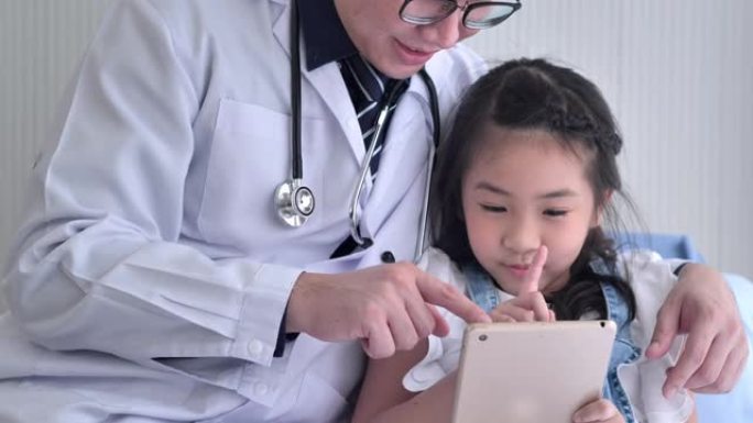 迷人的6岁亚洲小女孩与亚洲儿科医生男性在视频会议上与她的母亲或亲戚视频通话，在社交距离期间，以防止冠