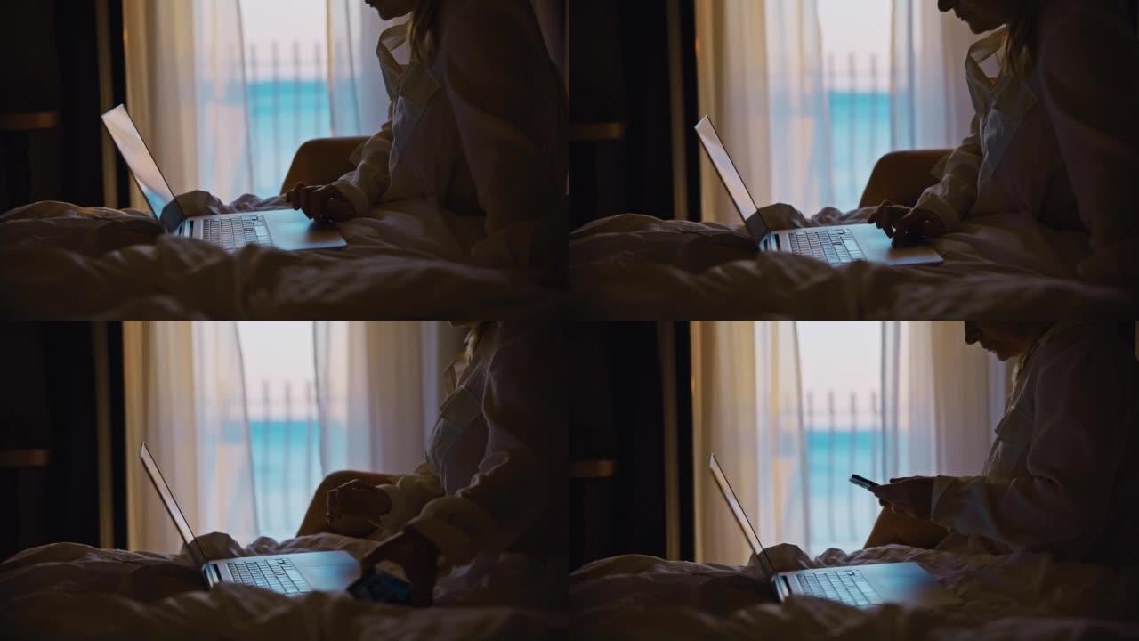 女人坐在酒店房间的床上，在笔记本电脑的触摸板上滚动，在智能手机上搜索信息