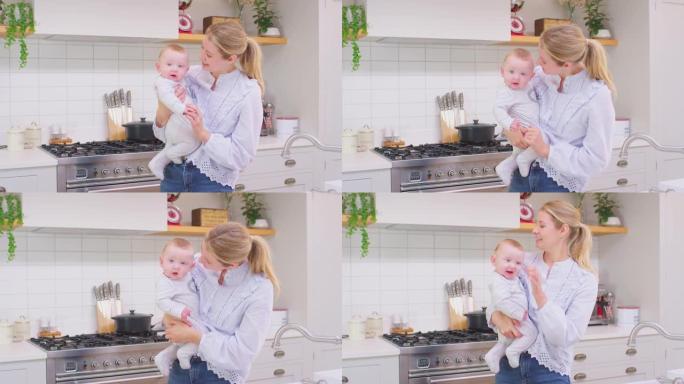 慈爱的母亲带着笑着的宝贝儿子在家里的厨房里一起玩游戏