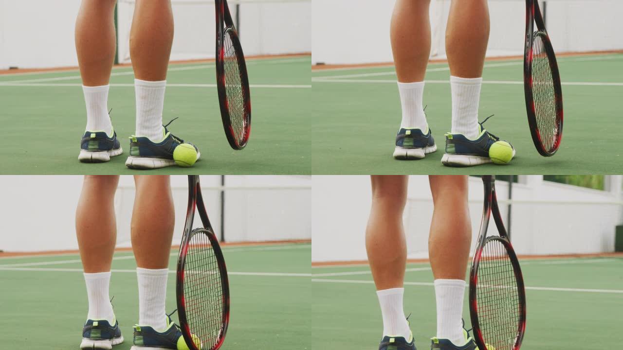 网球运动员用球拍和脚捡起球