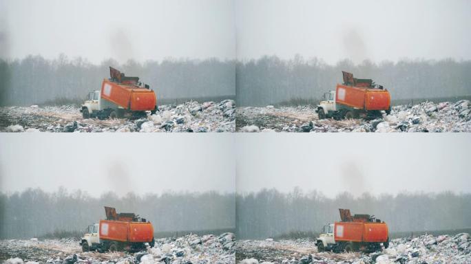 橙色卡车在垃圾场处理垃圾。