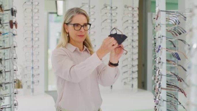 高加索女性验光师清洁眼镜在她的实践中出售。高级配镜师在眼镜店擦拭和检查眼镜，然后再出售带有复印空间的