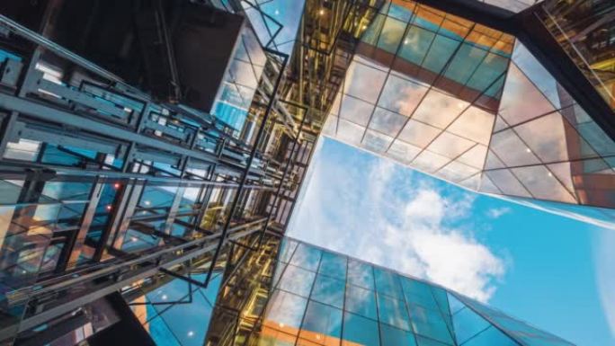 高层企业建筑摩天大楼的延时低角度，高层建筑与建筑中心的玻璃电梯之间的云反射