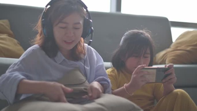 亚洲华裔妈妈享受周末闲暇与女儿用手机听音乐
