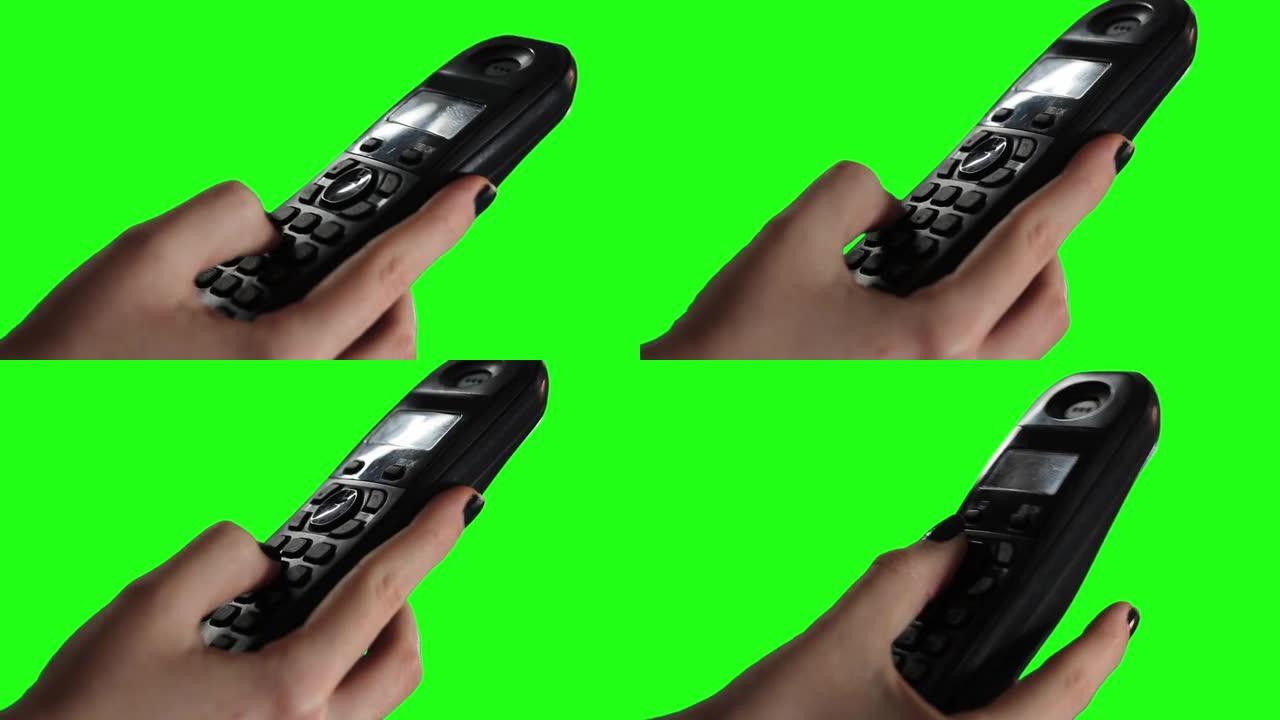 女性的手在绿屏上使用无绳旧电话。特写。