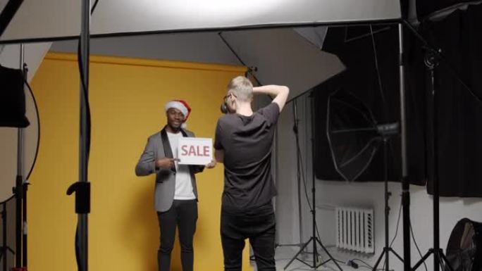幕后拍摄一名戴着圣诞帽的黑人男子，上面标有 “sale” 字样