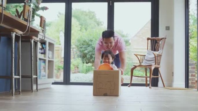 亚洲父子用垃圾模型的汽车在家里的厨房地板上推着儿子