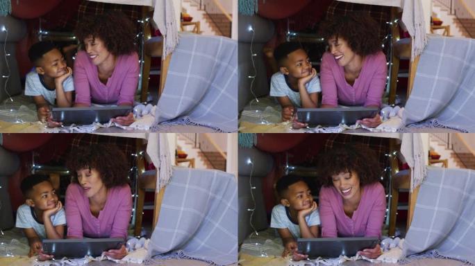 快乐的非洲裔美国母亲和儿子躺在用平板电脑制成的毯子房子里