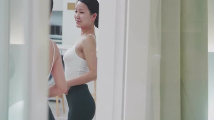 美丽的年轻亚洲女人看着镜子里的自己