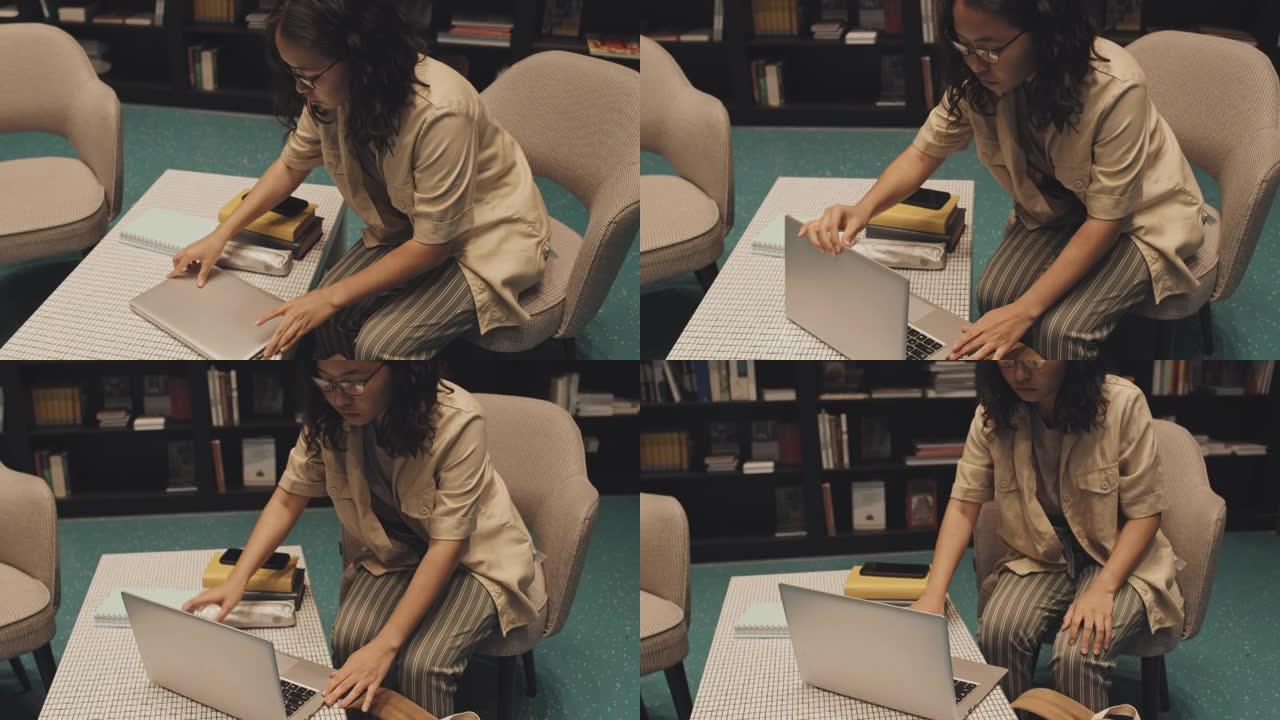 在图书馆的笔记本电脑上学习的女学生