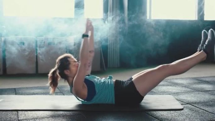 侧视图自我隔离锻炼。迷人的运动年轻女子在大气健身房的瑜伽垫上进行剧烈的腹肌运动