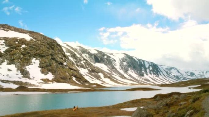 4k视频片段，两个无法识别的人在m ø reog Romsdal的一个湖附近搭起帐篷