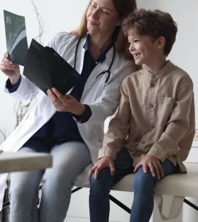 穿着白大褂的女医生向小男孩展示x射线