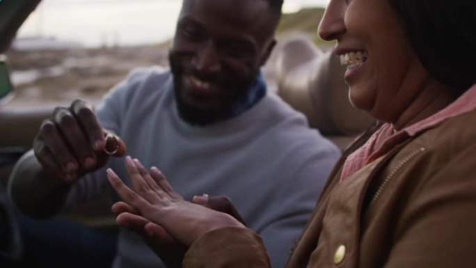非裔美国男子坐在敞篷车上给女友戴戒指