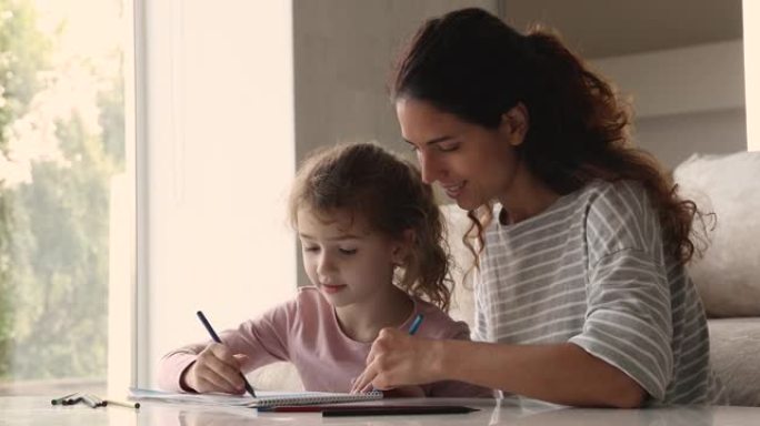 有爱心的妈妈和小女儿在素描本上用铅笔画画