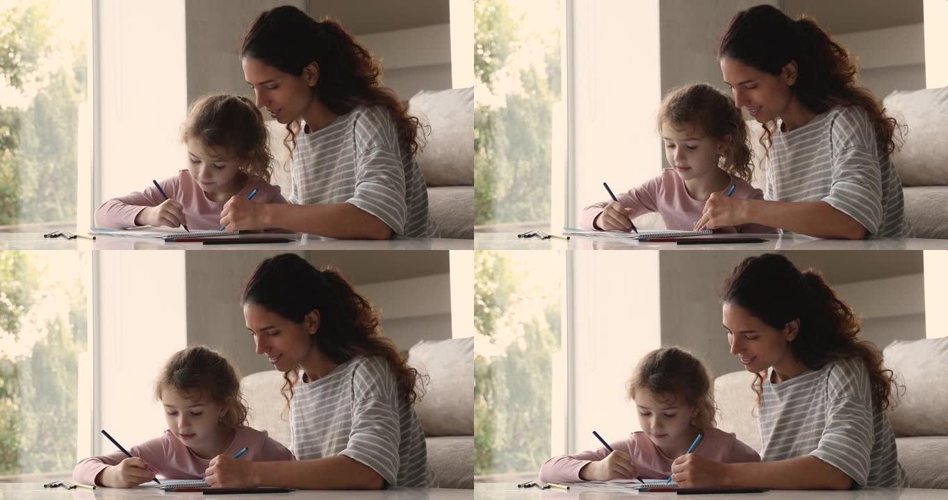 有爱心的妈妈和小女儿在素描本上用铅笔画画