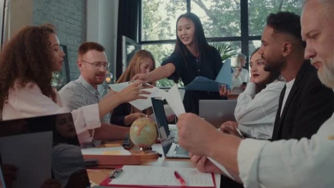 快乐的亚洲女性数据科学家经理在办公室慢动作为多种族同事进行销售推介