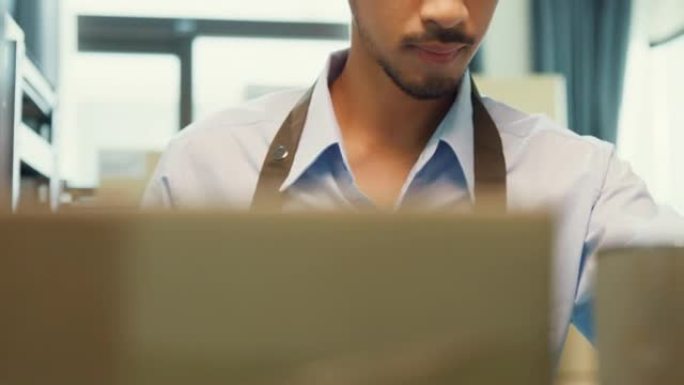 亚洲商业伙伴男士穿正式衬衫持有数字平板电脑检查库存在线库存数据在货架上的纸板箱为仓库交付客户。创业小
