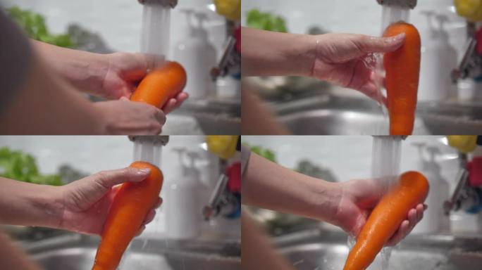 女人在厨房水槽里洗手新鲜胡萝卜的特写镜头: 健康的生活方式理念