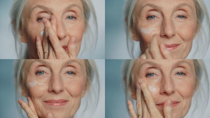 美丽的高级女人的肖像在眼霜下轻轻涂抹。老年女士用天然抗衰老化妆品使皮肤柔软、光滑、无皱纹。美容护肤、
