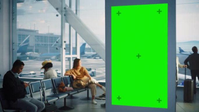 机场航站楼: 绿屏广告广告牌。带色度键的到达离开显示器。模型空间。背景: 一群人在航空枢纽的登机休息
