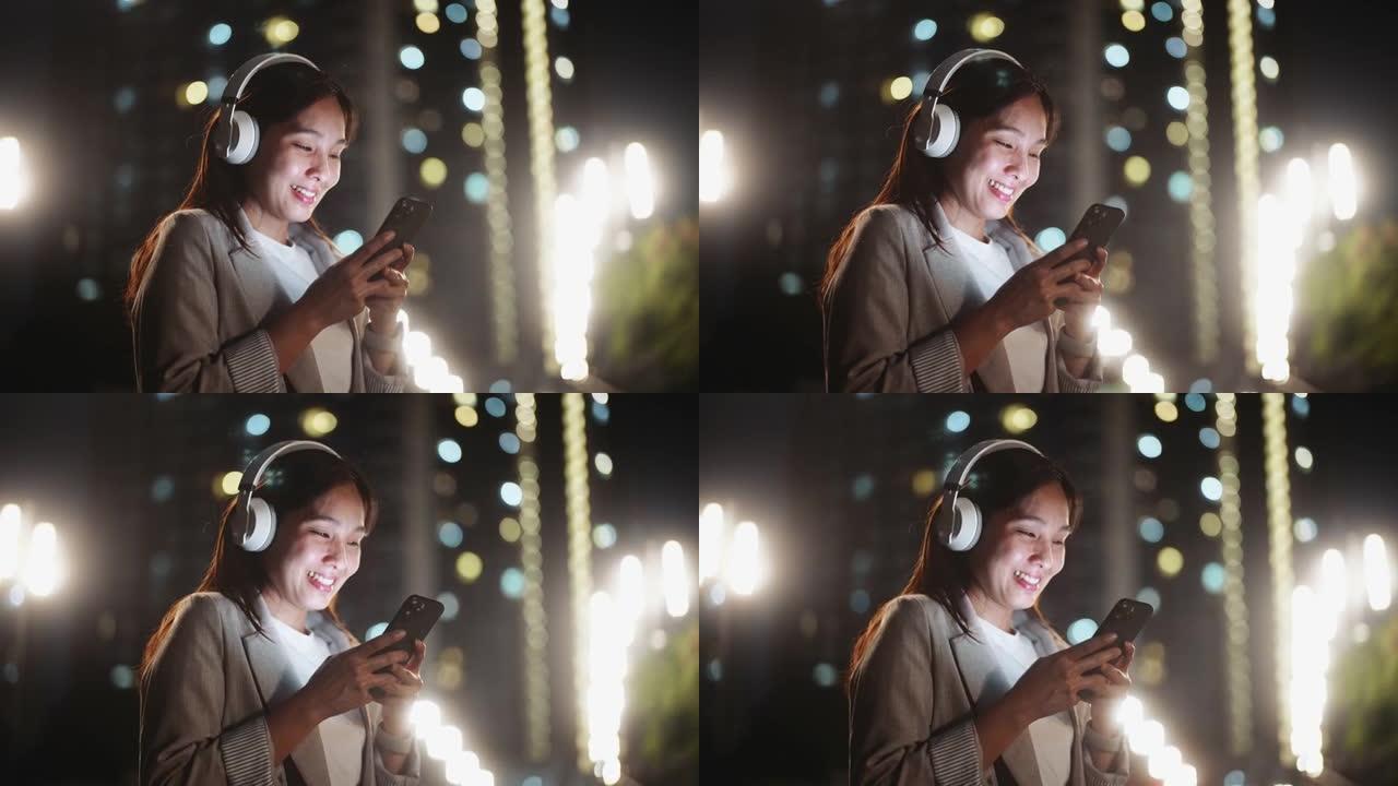 亚洲妇女使用智能手机在城市夜晚听音乐