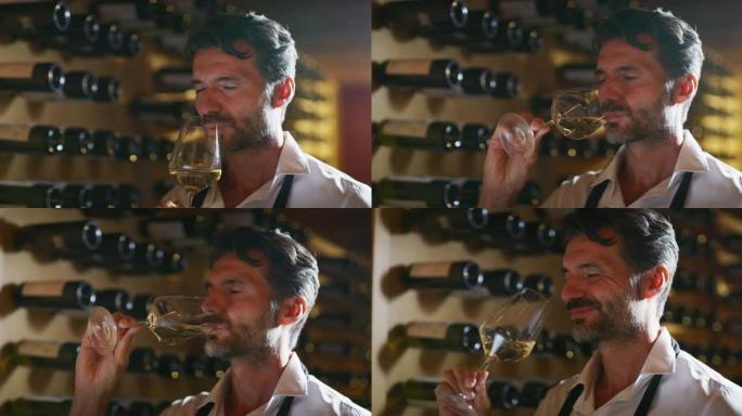 成功的男性侍酒师的真实照片正在品尝一种风味，并检查倒入酒窖透明玻璃杯中的白葡萄酒质量。