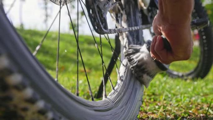 SLO MO无法识别的人使用刷子清洁山地自行车的车轮