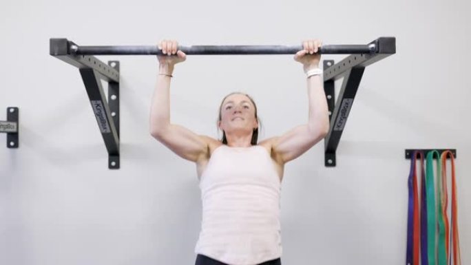 健身的年轻女子在健身房的酒吧里做俯卧撑