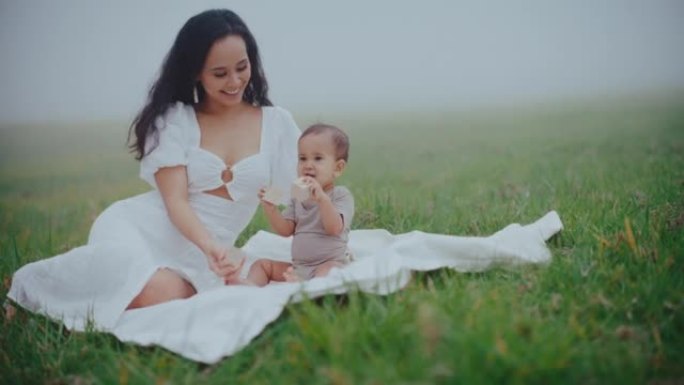 母亲和年幼的婴儿躺在草地上的妈妈孩子婴儿