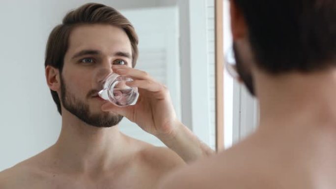快乐的男人享受日常保健习惯，在浴室里解渴。