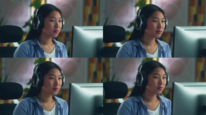 戴着耳机的亚洲女性在电脑上工作