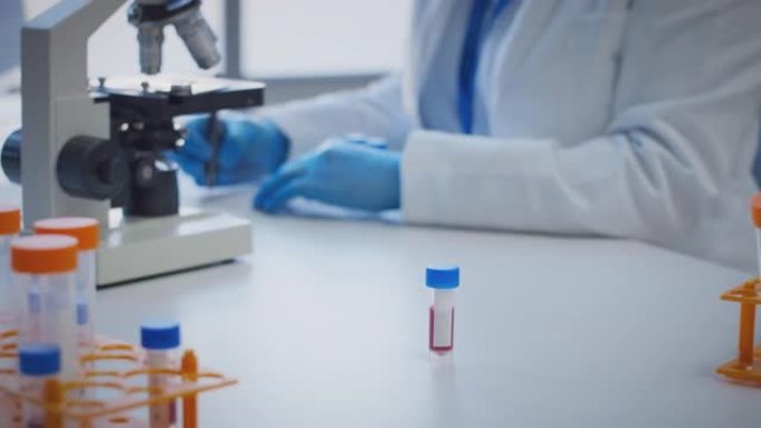 使用显微镜保存带有空白标签的血液样本进行研究的实验室工作人员的特写
