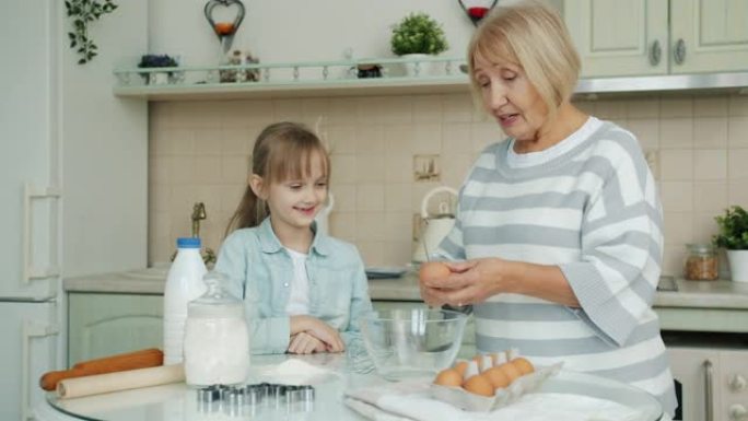 祖母和孙女在厨房做饭，在碗里打鸡蛋说话