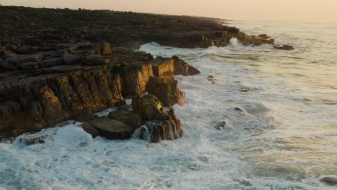 日落时分，在南非东开普省姆坎巴蒂自然保护区崎rock不平的岩石海滩海岸线上的海浪的鸟瞰图