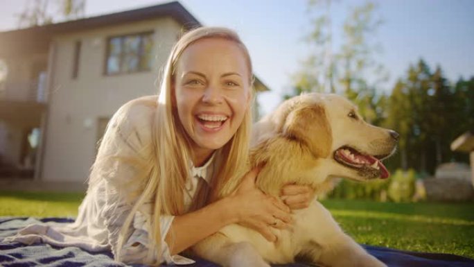 年轻漂亮的女人在户外野餐时拥抱她的金毛寻回犬血统狗，向相机挥手致意。与朋友交谈并重新开始。POV视频