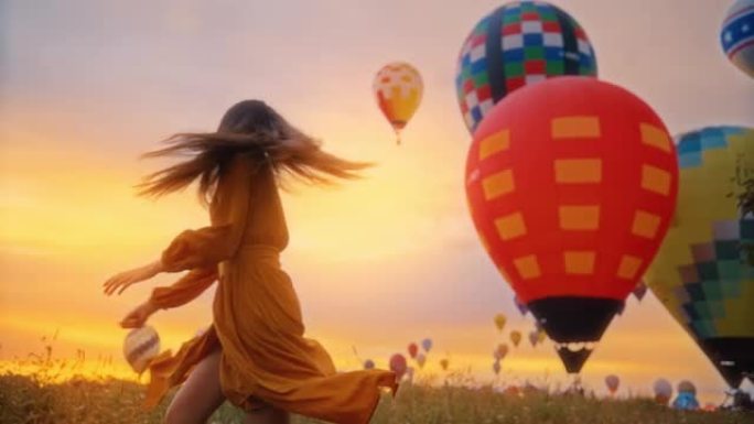 无忧无虑的年轻女子带着热气球在日出场旋转