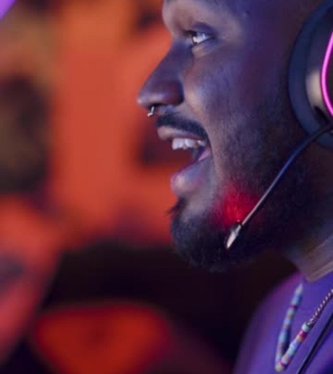 垂直屏幕: 专业的黑人玩家在电脑上玩在线视频游戏。近距离拍摄戴着耳机的年轻人的肖像，与玩家在PvP锦