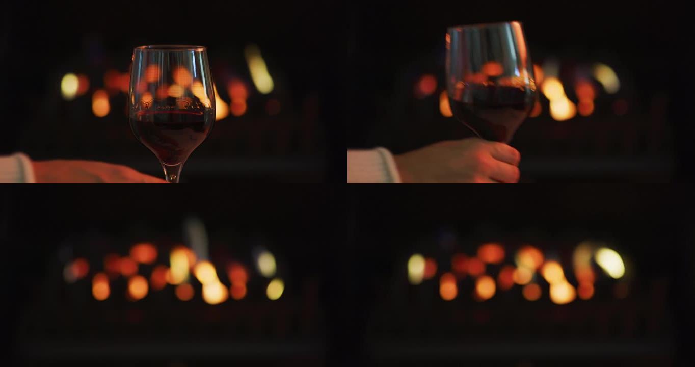 4k视频片段，一个无法辨认的女人在家里的火炉前拿起一杯酒