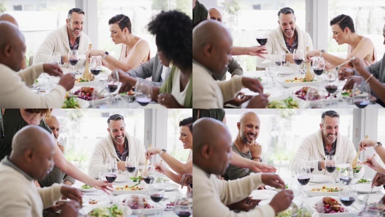多样化和成熟的朋友群在家里的餐桌旁吃饭、喝酒和吃午餐。快乐的同事一边享受美食和美酒，一边在餐厅一起吃