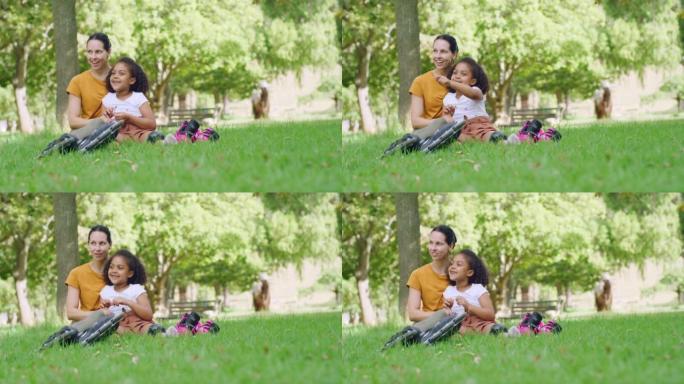 快乐的慈爱的母亲和她可爱的收养的小孩在公园的草地上放松和交谈。微笑的女人和女儿在花园里度过的家庭日，